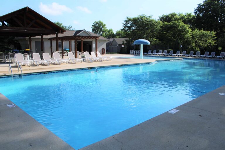 Operational community pool with clear blue water lounge chairs umbrellas and shaded structure