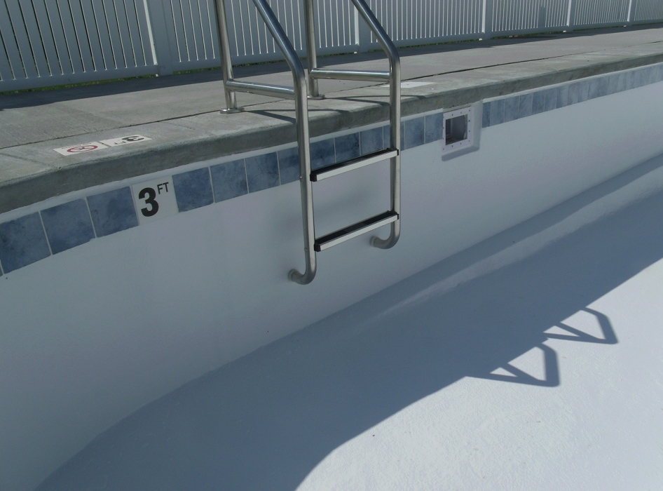 A dry, empty swimming pool with a metal ladder and a depth marking of 3 feet on the side. The area is well-lit, casting sharp shadows.