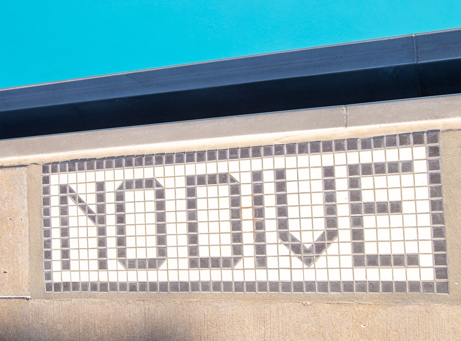 Tiled wall with mosaic text no dive safety signage