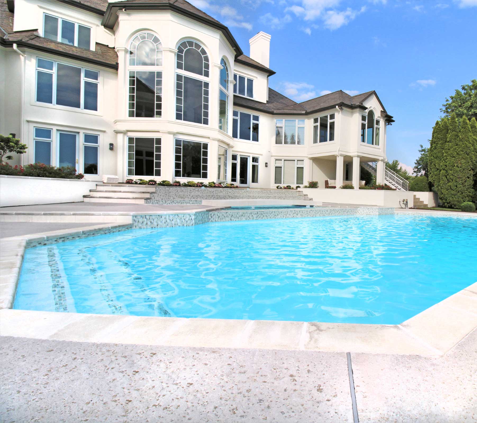 Luxury residential swimming pool with large house — upscale pool design and renovation inspiration