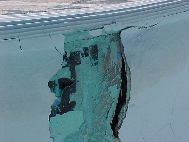 Damaged pool wall with exposed material and cracks — pool structural repair and renovation project.