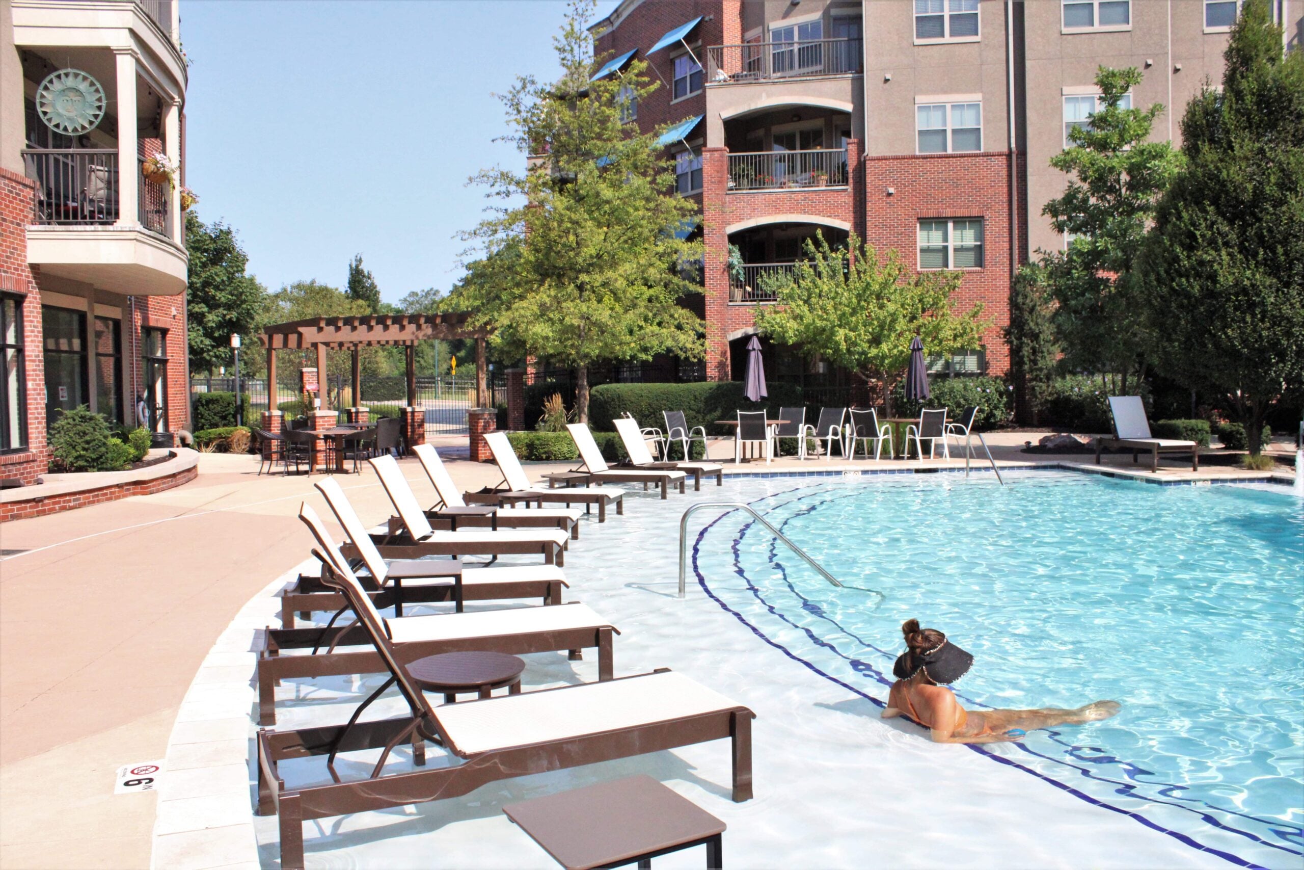 Clean outdoor swimming pool with lounge chairs and person relaxing — residential or hotel pool design and renovation
