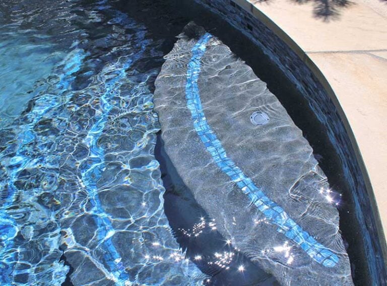Close-up of pool steps illuminated by sunlight — safe pool entry design and tile installation.
