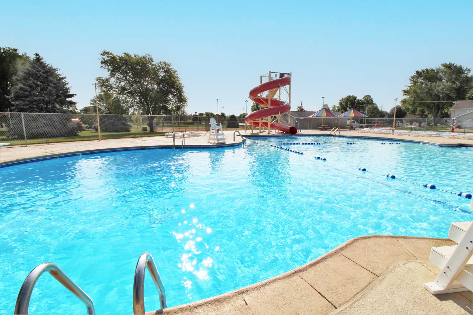 Public swimming pool with clear blue water and red spiral slide — family‑friendly aquatic facility design and renovation