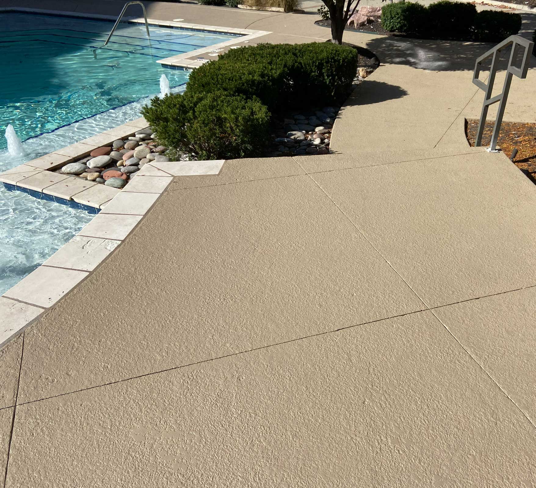 Poolside area with textured flooring and landscaping — residential pool deck renovation and design