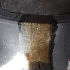 A close-up of a metal surface with a rectangular patch of yellowed material applied. There are signs of wear and aging, imparting a rustic feel.