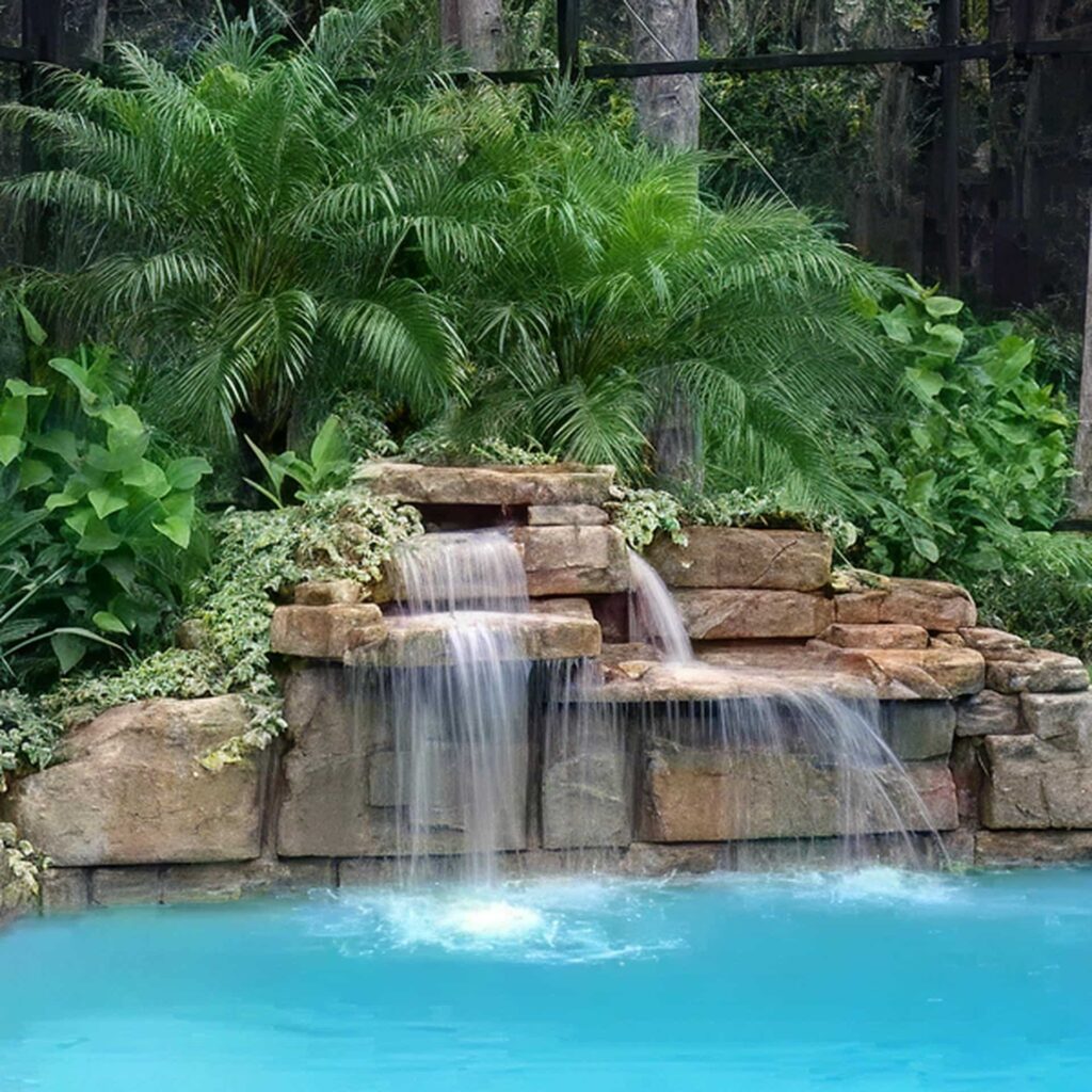 A serene waterfall flows over stacked rocks into a turquoise pool, surrounded by lush green foliage, conveying a tranquil and tropical ambiance.