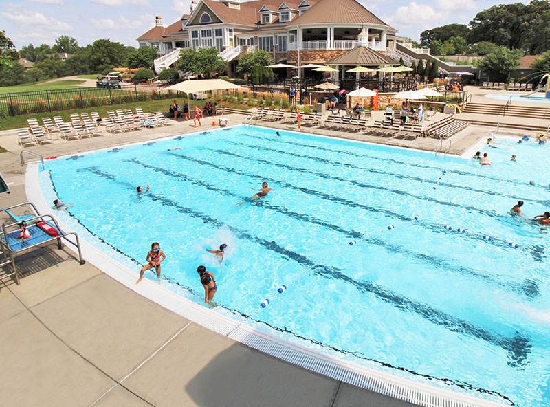 Large outdoor swimming pool with lane markers and swimmers — competitive pool renovation and aquatic facility design