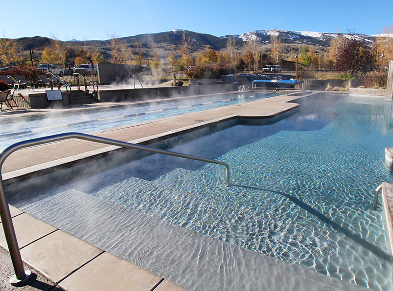 Steaming outdoor swimming pool with mountain backdrop — luxury pool design and spa renovation.