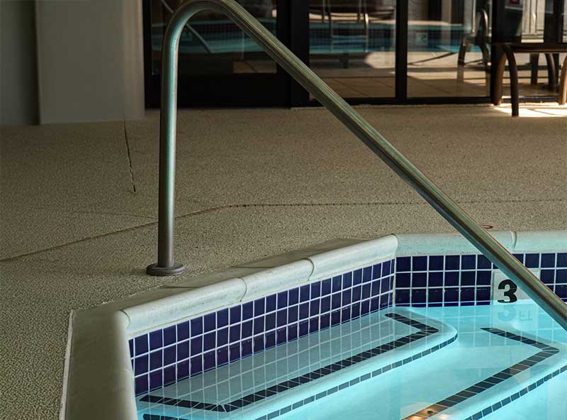 Pool entry steps with handrail and blue tiles — safe pool access and step design.