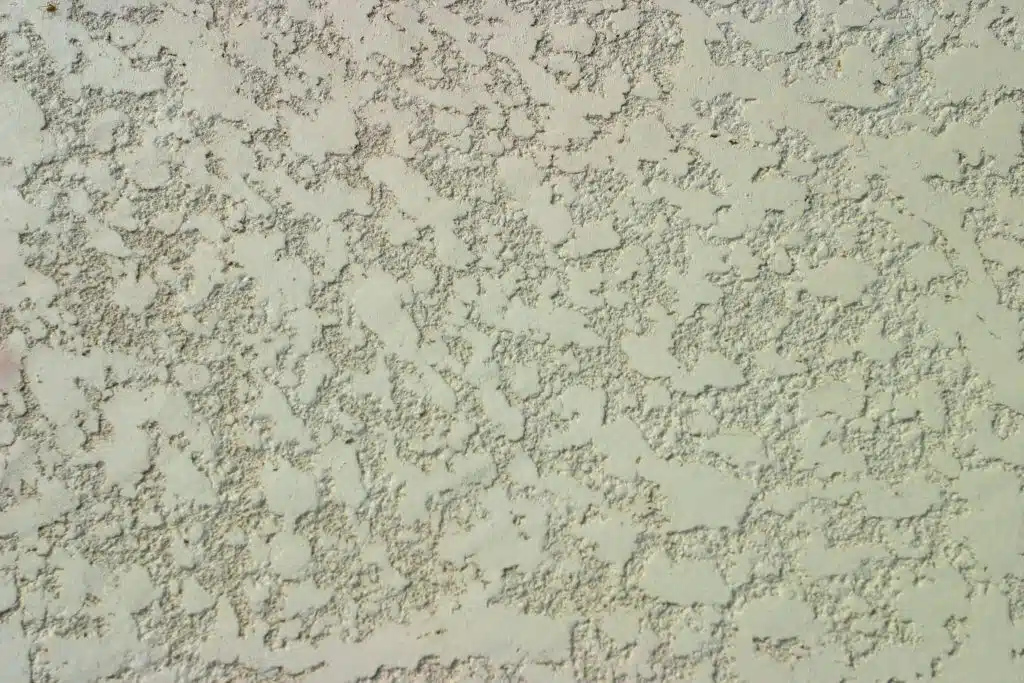 Close‑up of textured pool deck or wall finish with stucco‑like pattern — swimming pool surface design and renovation detail