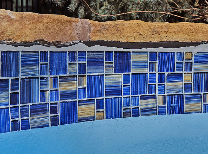 Swimming pool with custom decorative tile pattern in blue and yellow — luxury pool design and customization.