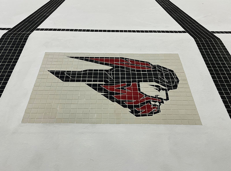 Tile mosaic of stylized bird emblem — custom swimming pool tile artwork and branding