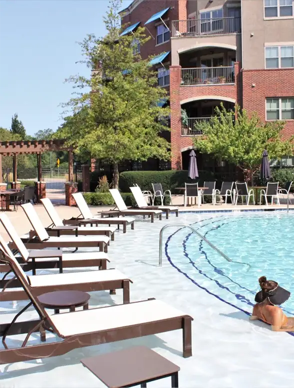 Clean outdoor swimming pool with lounge chairs and person relaxing — residential or hotel pool design and renovation