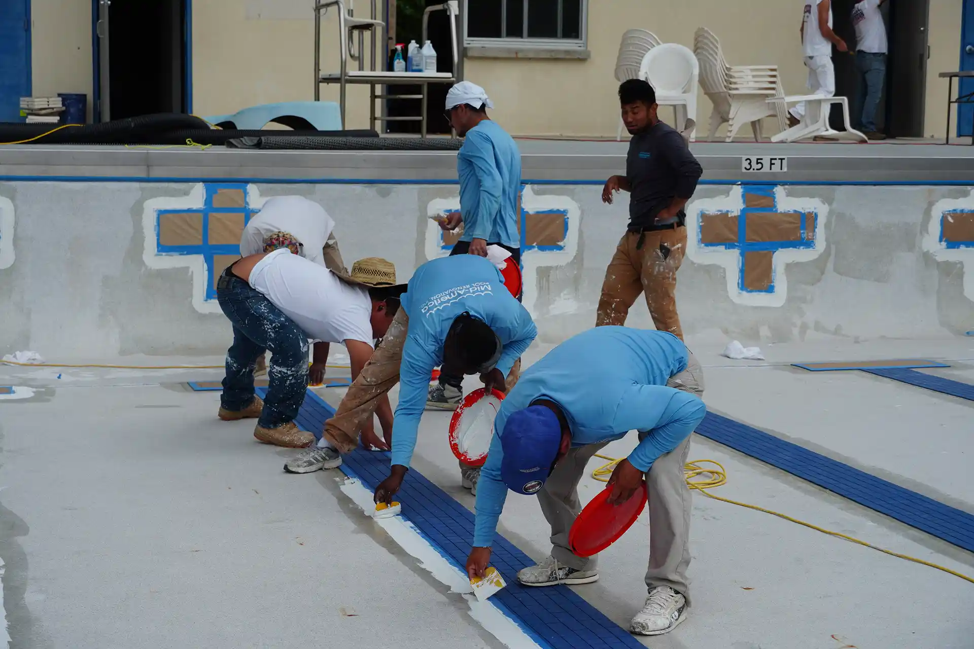 A group of workers is painting a pool.