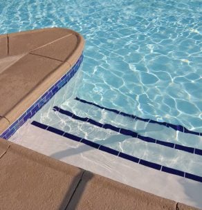 Close‑up of pool edge with tiled border and steps — pool entry design and tile installation
